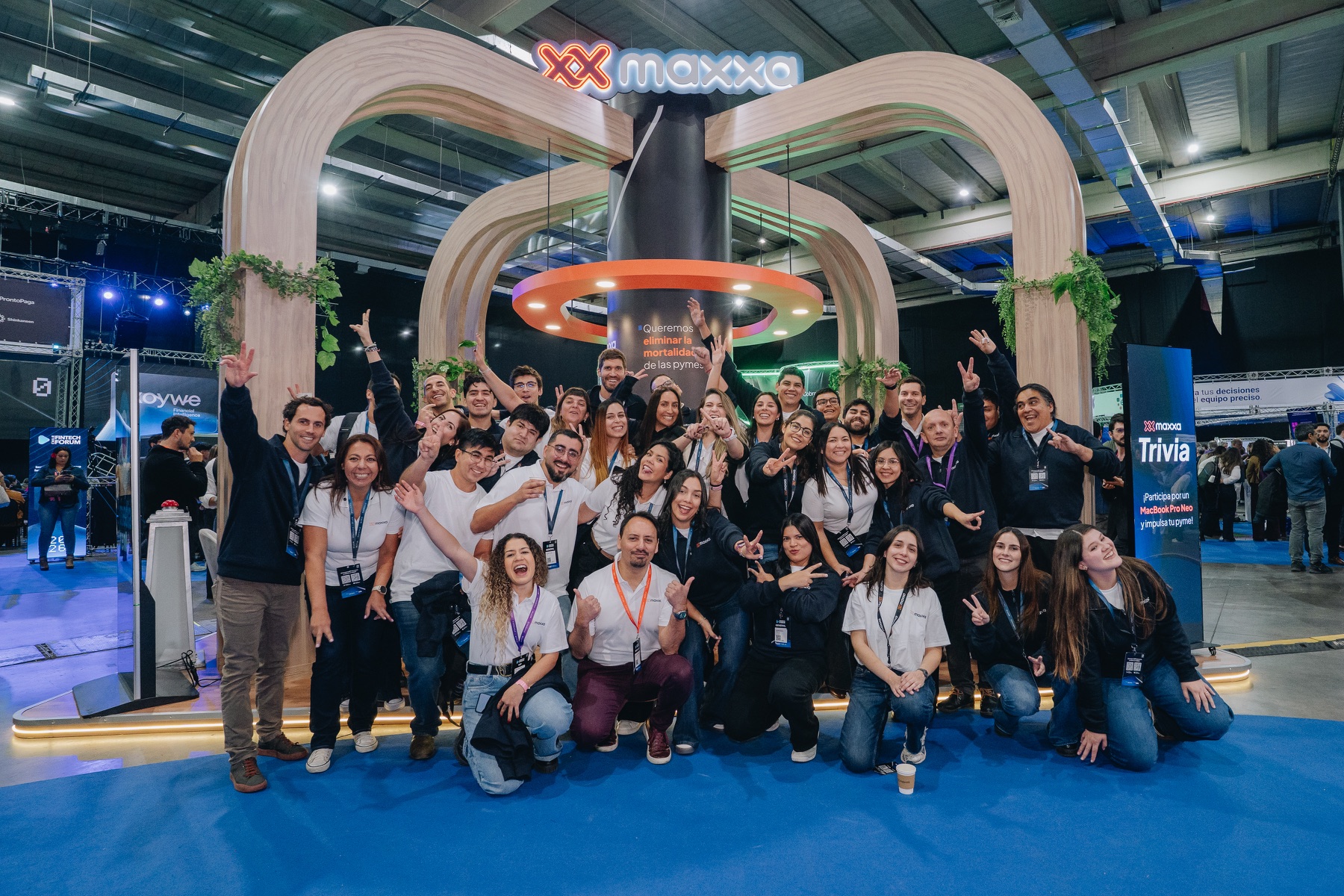 Grupo de participantes bajo los arcos iluminados del stand de Maxxa en Chile Fintech Forum
